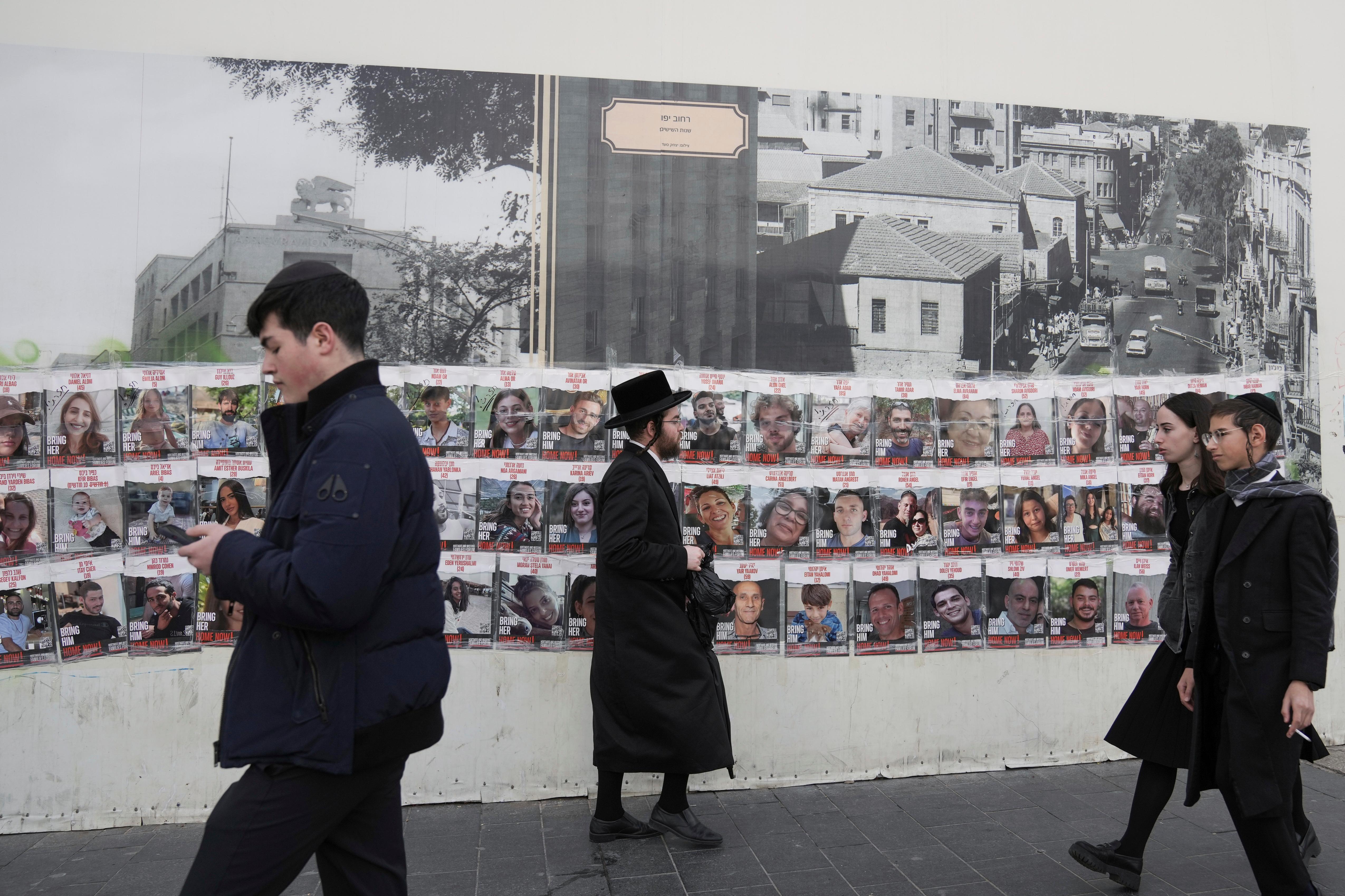 People pass by a wall with photos of about 240...