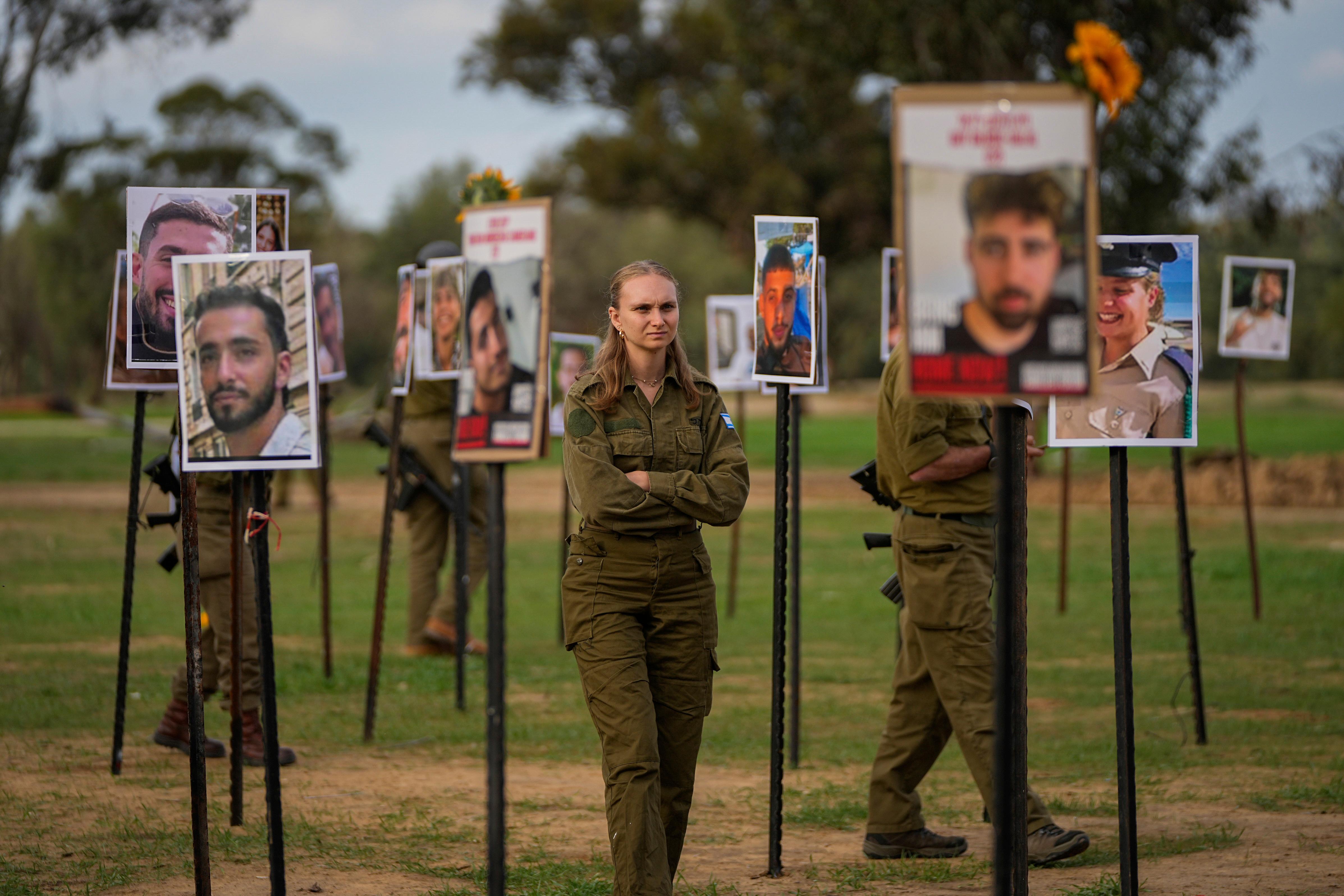 Israeli soldiers look at photos of people killed and taken...